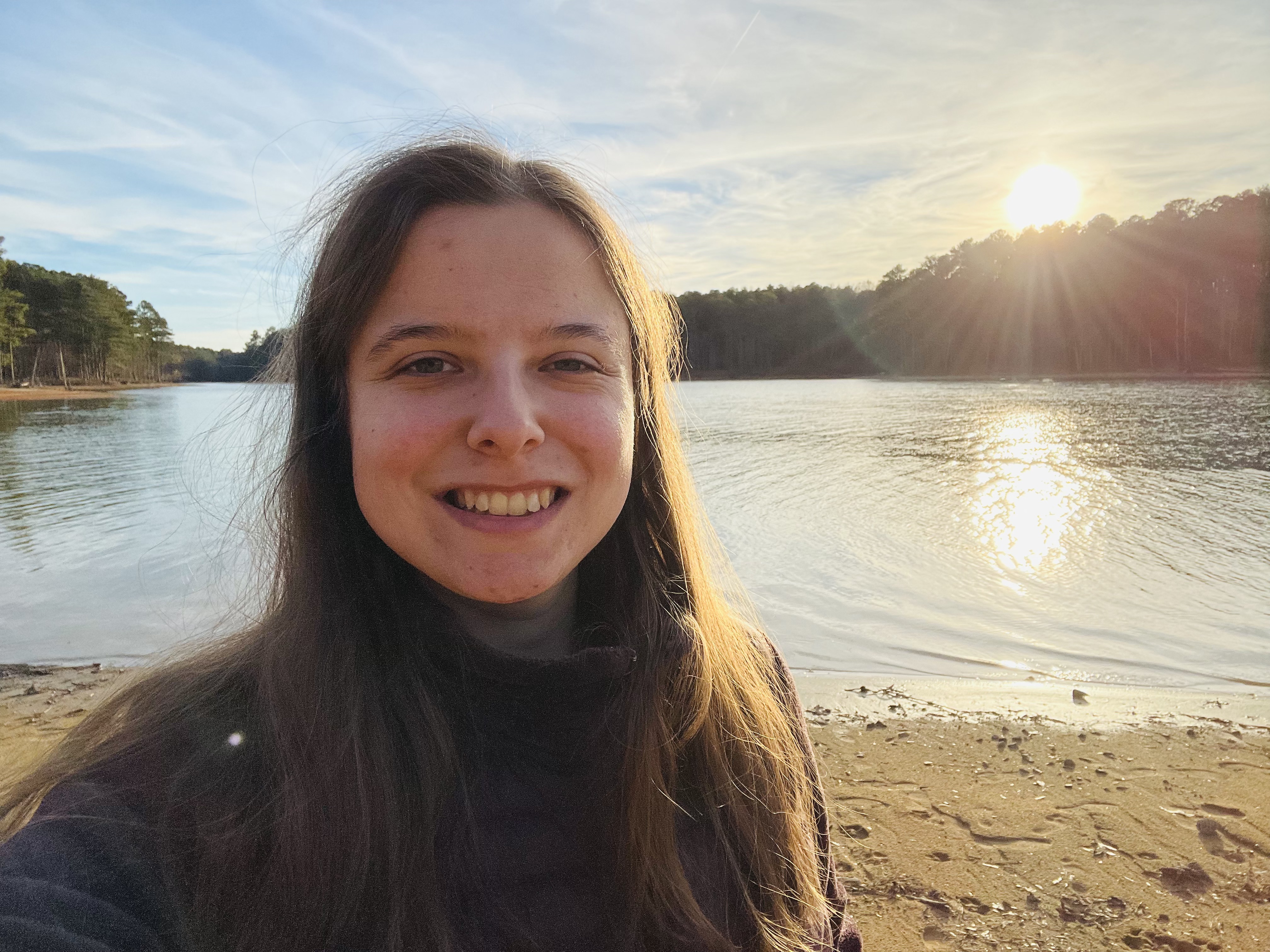 Maddie Norwood smiling and standing in front of a lake